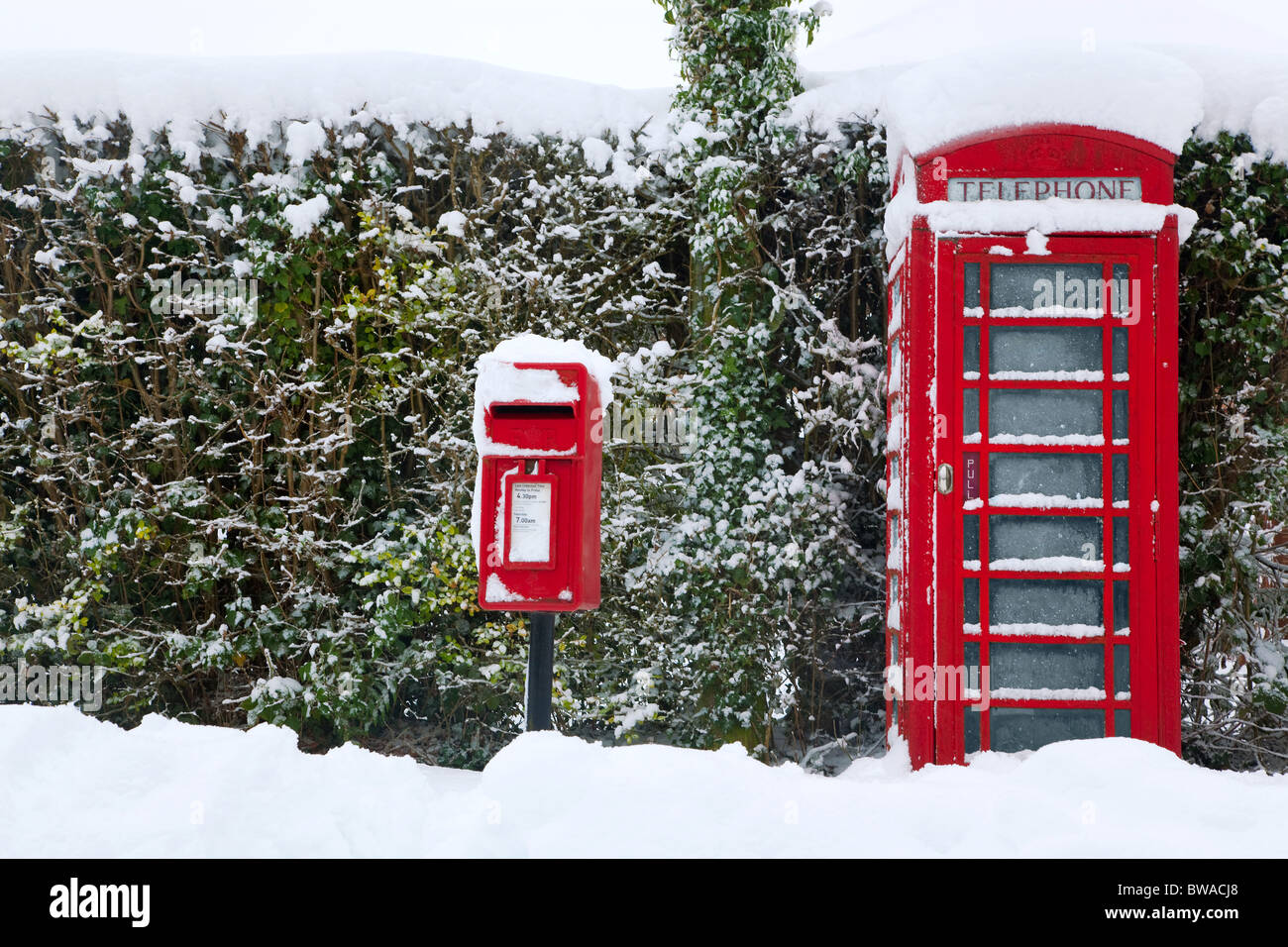 Un téléphone public anglais rouge traditionnel et post box après une forte chute de neige. Banque D'Images