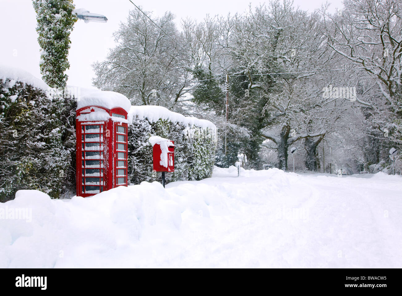 Un téléphone public anglais rouge traditionnel et post box après une forte chute de neige. Banque D'Images