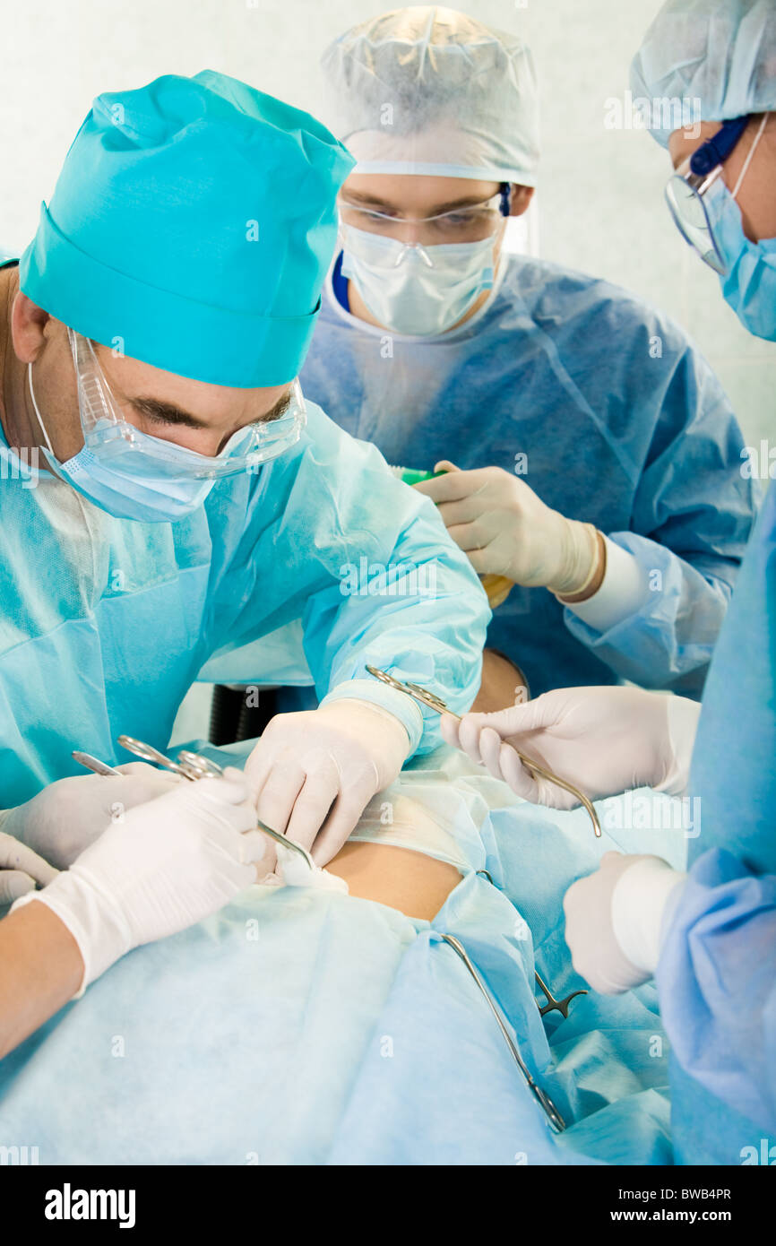 Groupe de chirurgiens qui rendent son utilisation sur le ventre du patient en clinique Banque D'Images