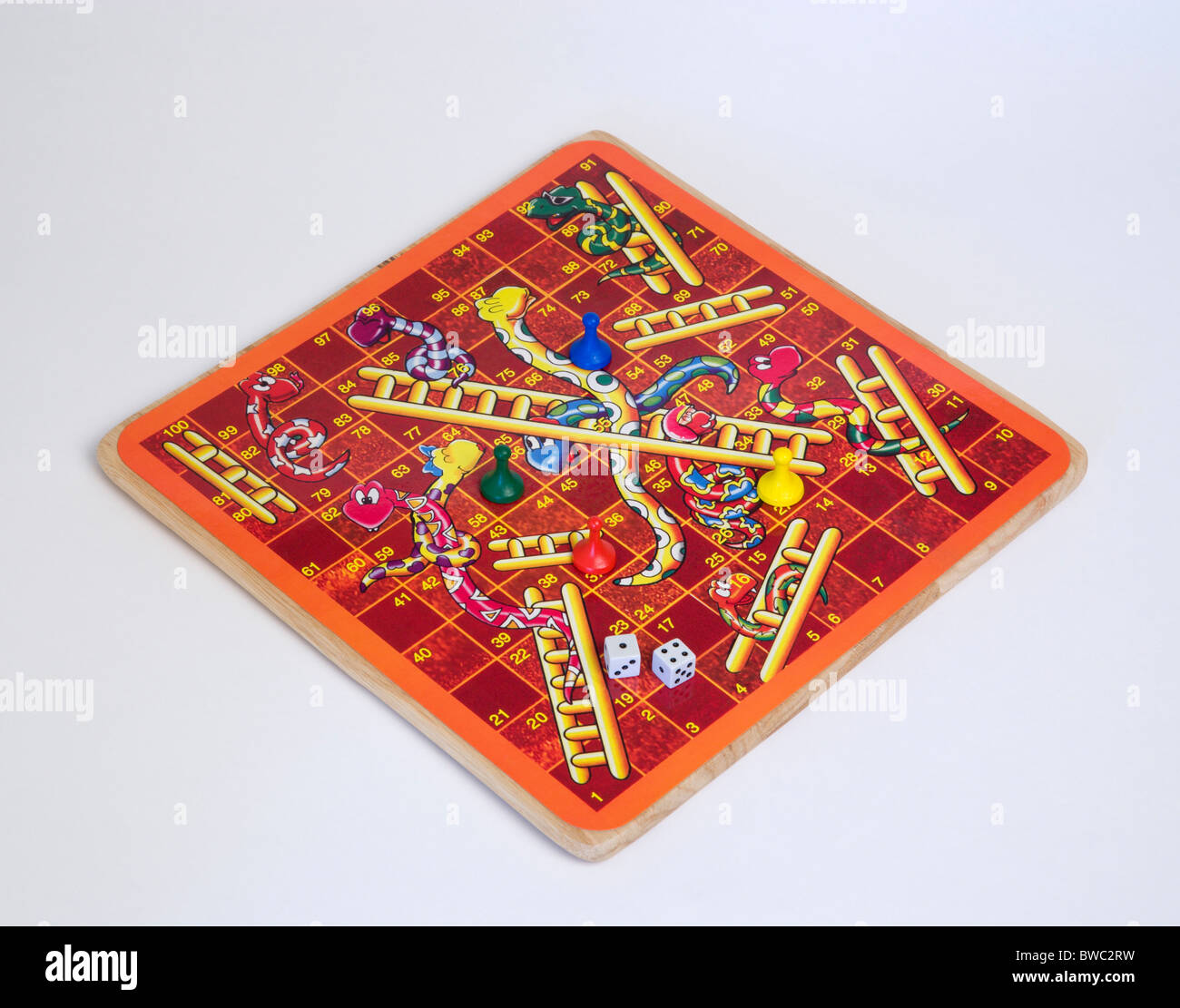 Jouets, jeux, jeu de société, jeu de serpents et échelles avec des dés et des compteurs pour les enfants sur un fond blanc. Banque D'Images