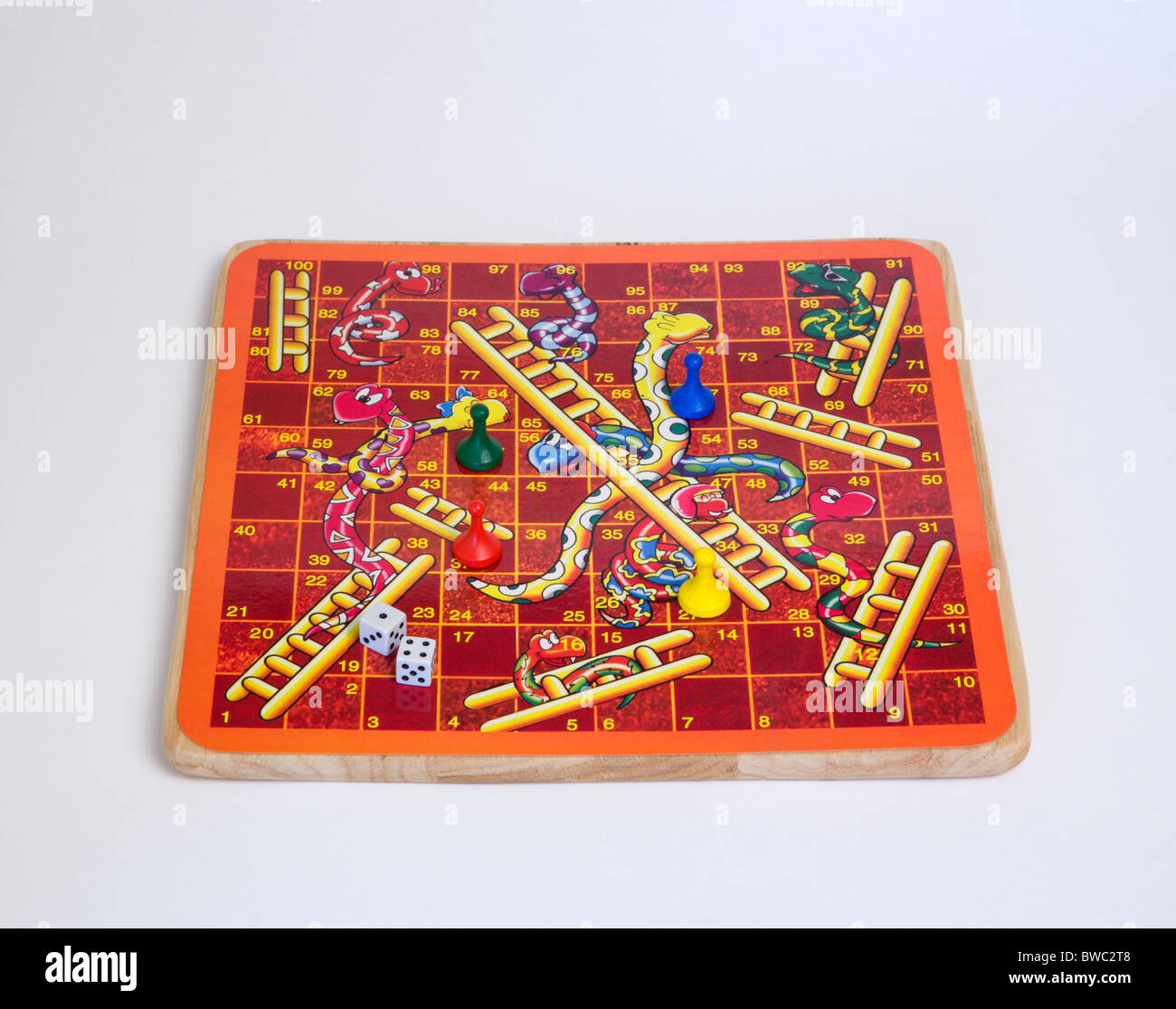 Jouets, jeux, jeu de société, jeu de serpents et échelles avec des dés et des compteurs pour les enfants sur un fond blanc. Banque D'Images