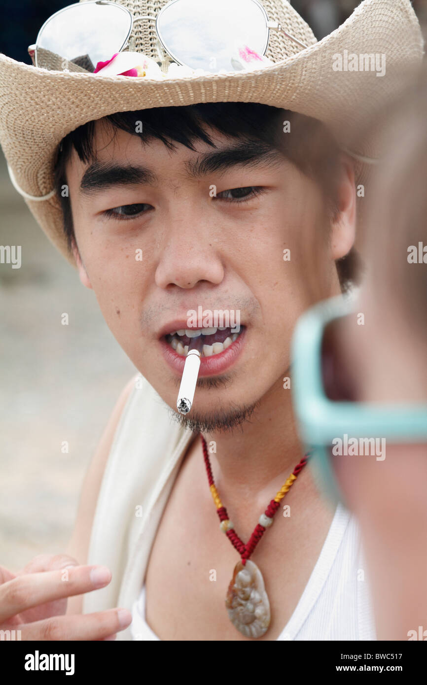 Les jeunes adultes chinois touriste avec chapeau et cigarette dans sa  bouche. Close up soin du visage. Pattaya, Thaïlande, Octobre 2010 Photo  Stock - Alamy