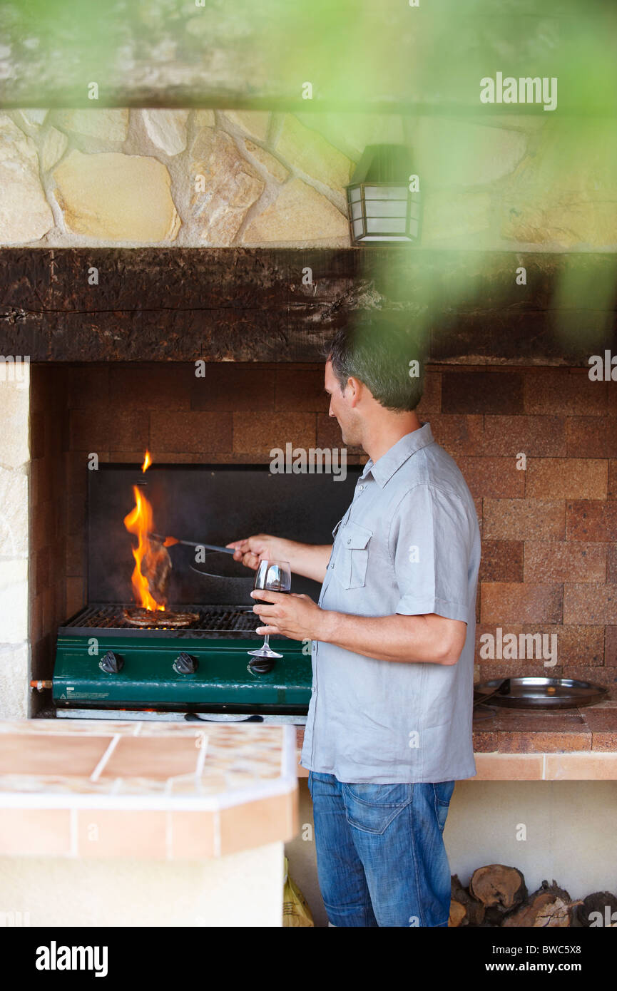 Homme debout par barbecue Banque D'Images Homme debout par barbecue Banque D'Images