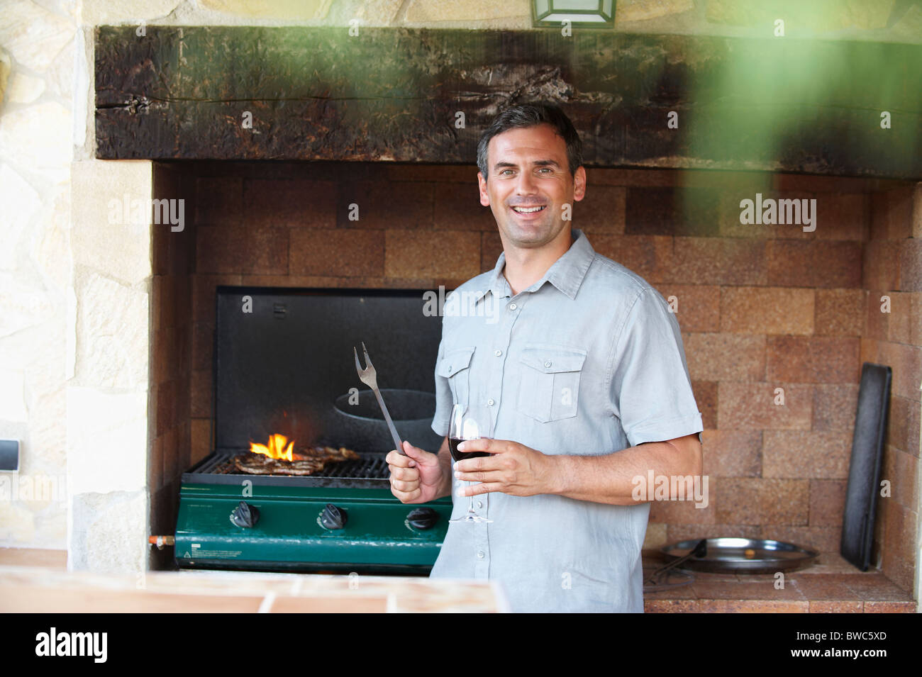 Smiling man standing by barbeque Banque D'Images Smiling man standing by barbeque Banque D'Images