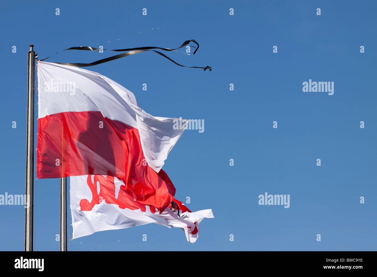 Le drapeau national polonais et l'indicateur de Solidarnosc (Solidarité) - à la fois avec des rubans deuil - contre le ciel bleu Banque D'Images