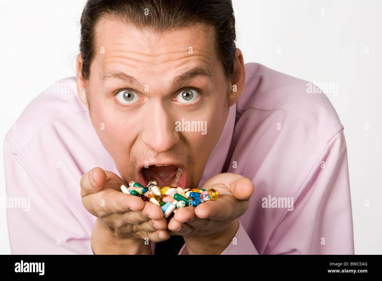 Photo de l'homme effrayé à pleine bouche holding pills et les manger Banque D'Images