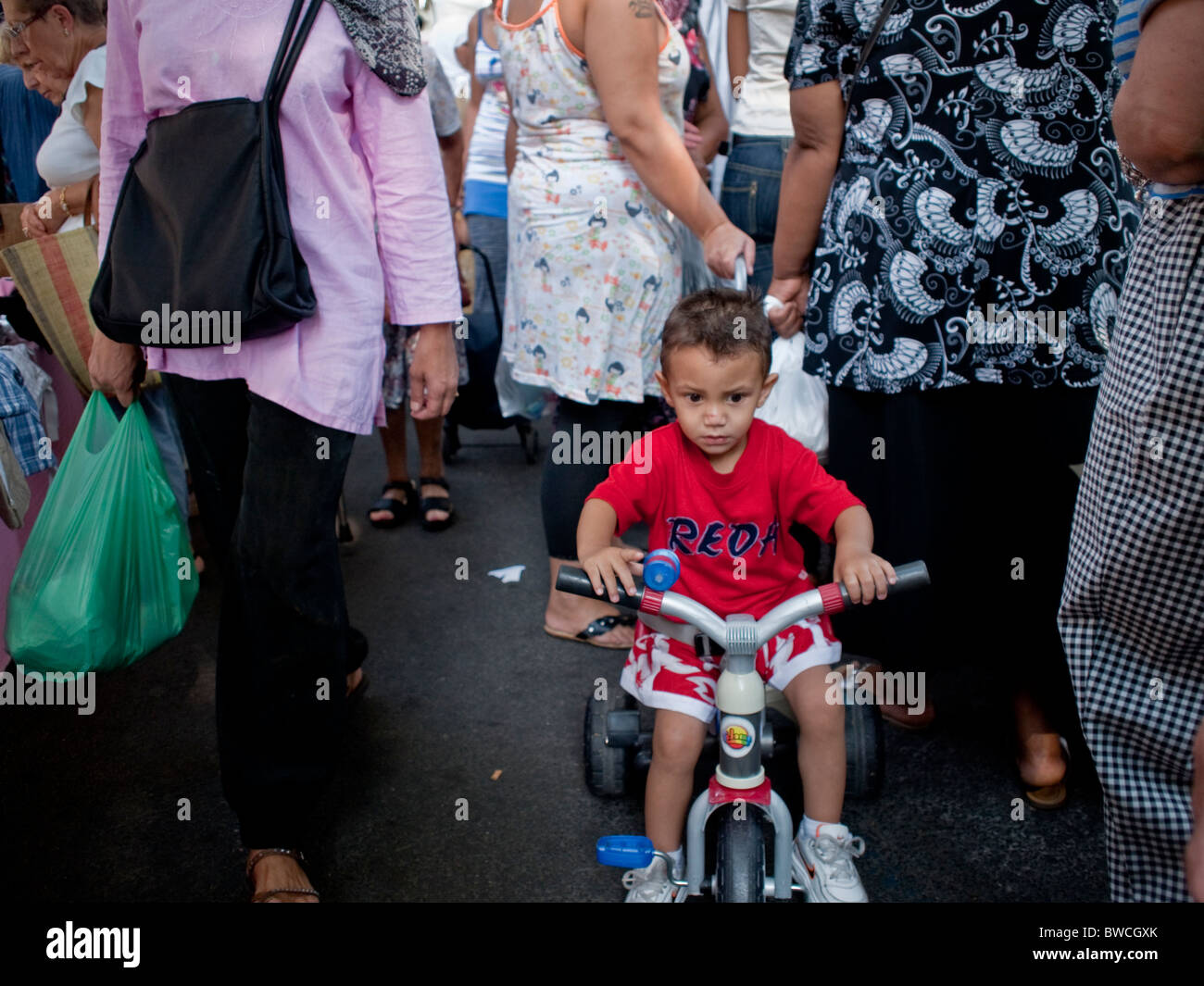 Petit garçon sur un tricycle à un marché bondé à Perpignan dans le sud-ouest de la France Banque D'Images