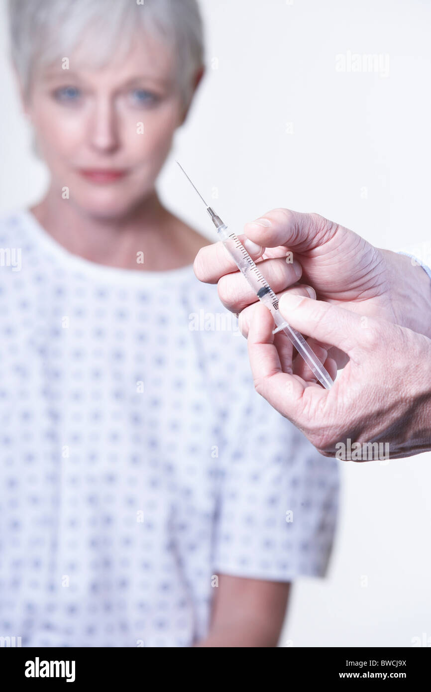 États-unis, Californie, Fairfax, Doctor's hands holding syringe, female patient in background Banque D'Images