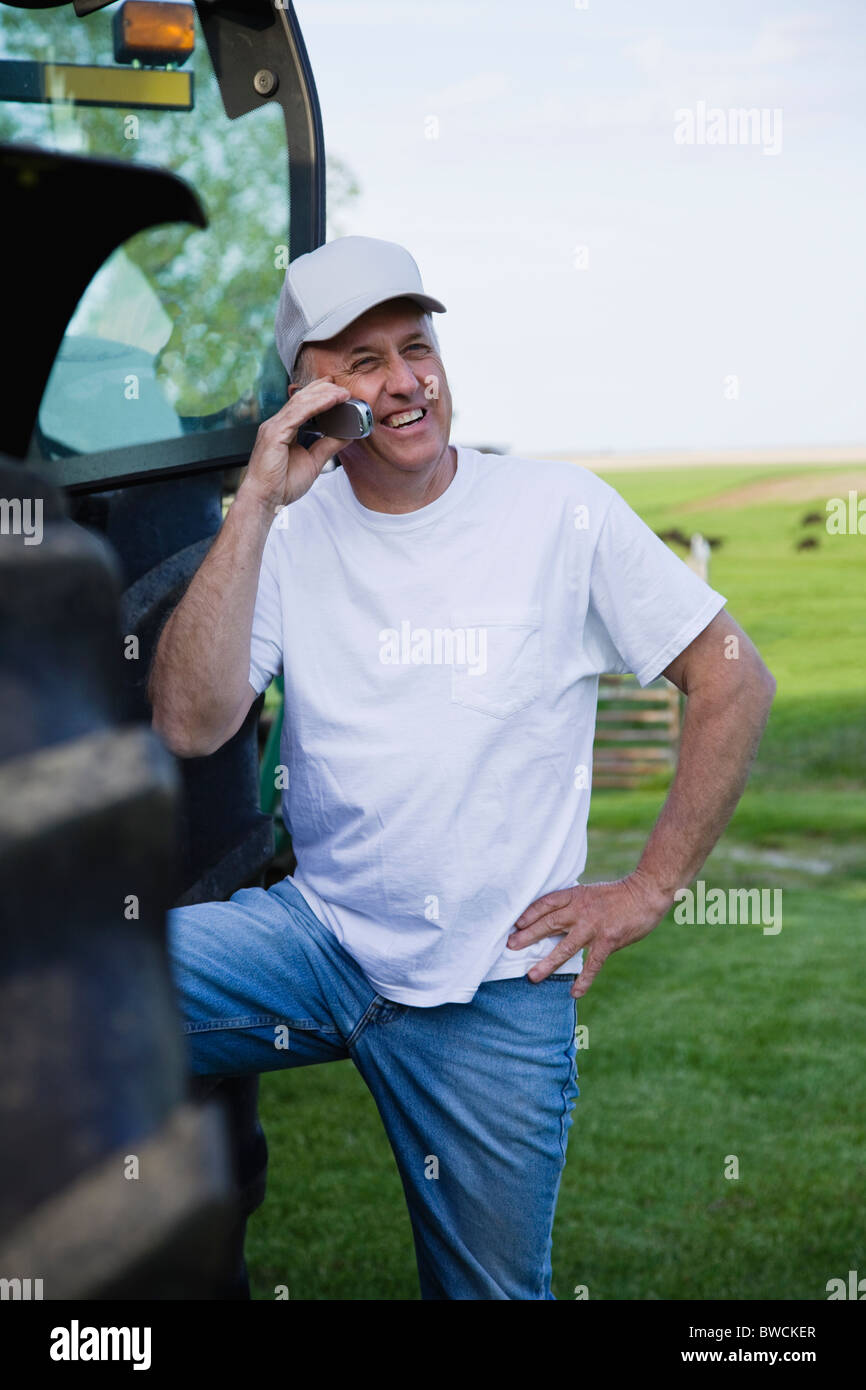 États-unis, Illinois, Metamora, agriculteur à l'aide de téléphone mobile par le tracteur dans le champ, Banque D'Images