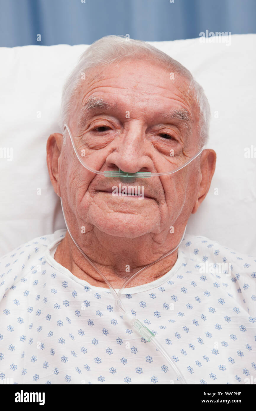 États-unis, Illinois, Metamora, Portrait of senior man with canule nasale oreille allongé in hospital bed Banque D'Images