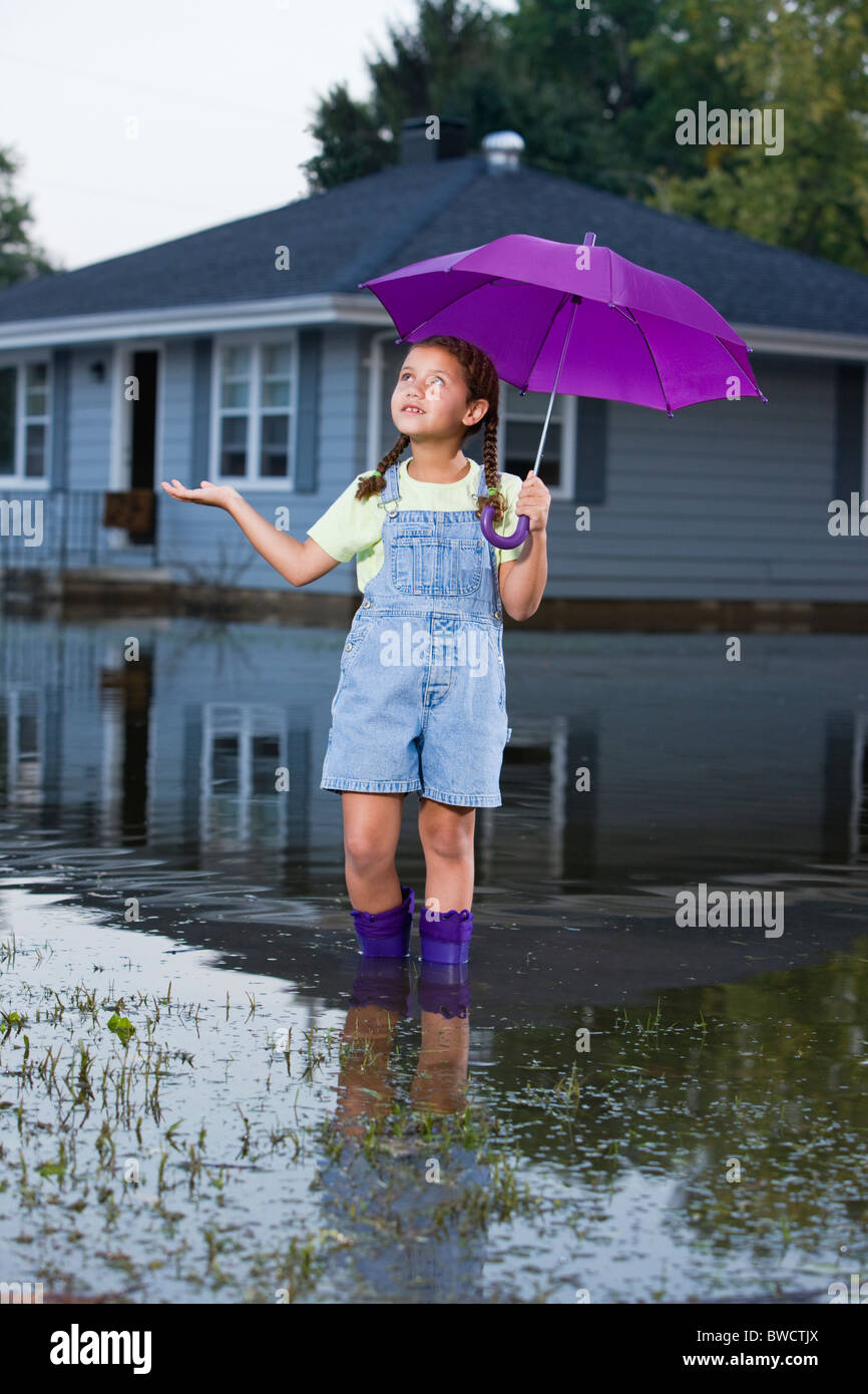 États-unis, Illinois, Chillicothe, mixed race girl (8-9) dans l'eau et holding umbrella Banque D'Images