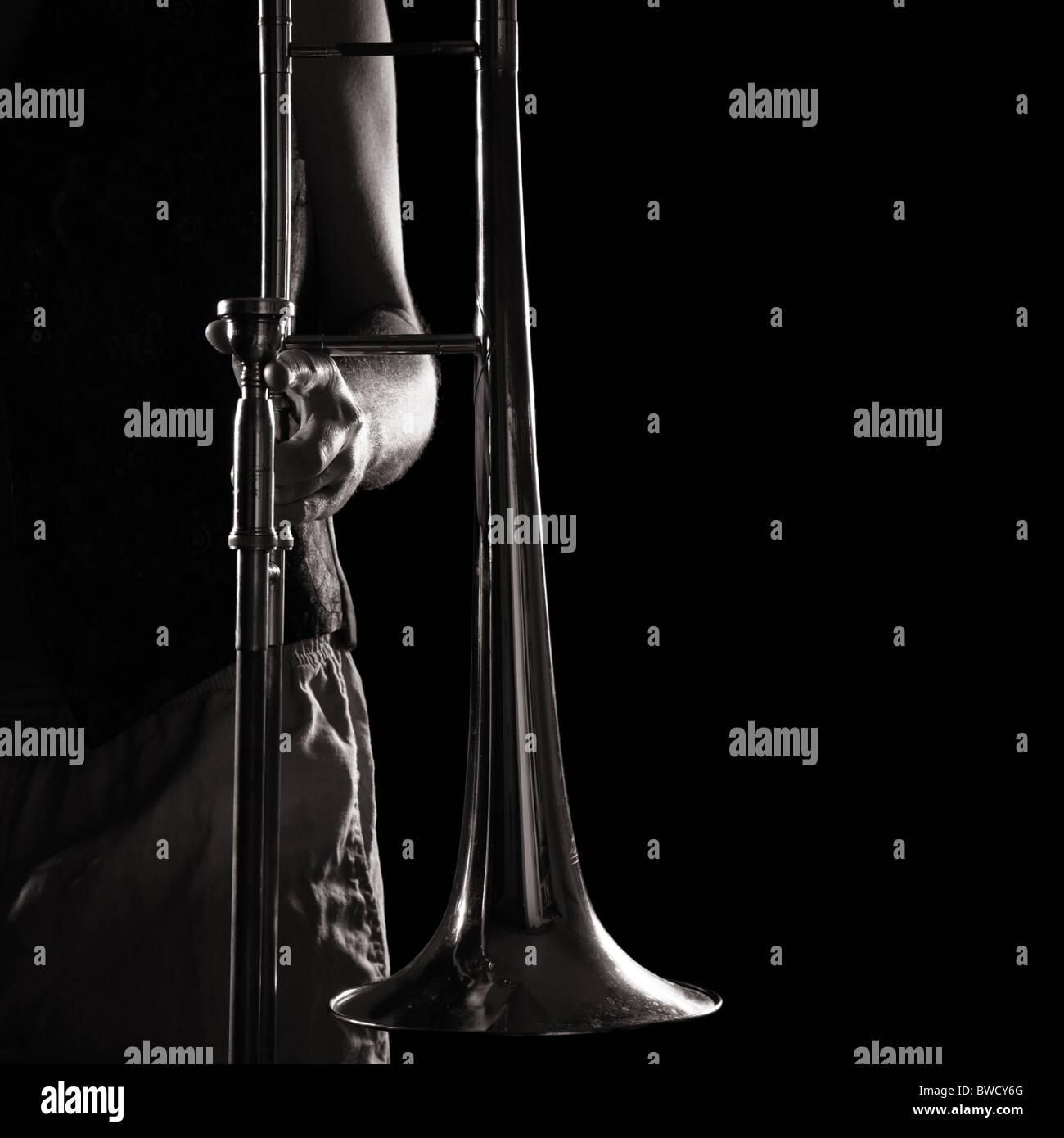 Homme tenant un trombone une forte lumière latérale contrastante ; version monochrome Banque D'Images