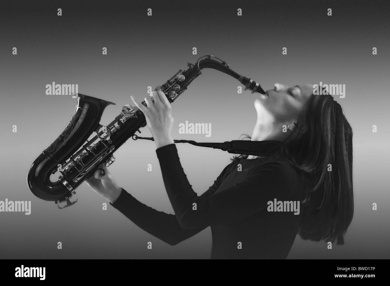 Jeune femme en noir avec le saxophone. Banque D'Images