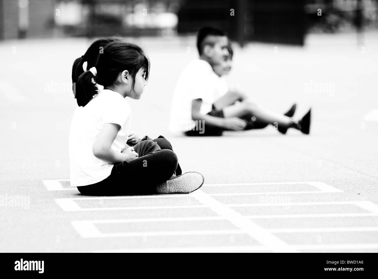 Des enfants assis dans une aire de jeux, un haut contraste noir et blanc. Banque D'Images