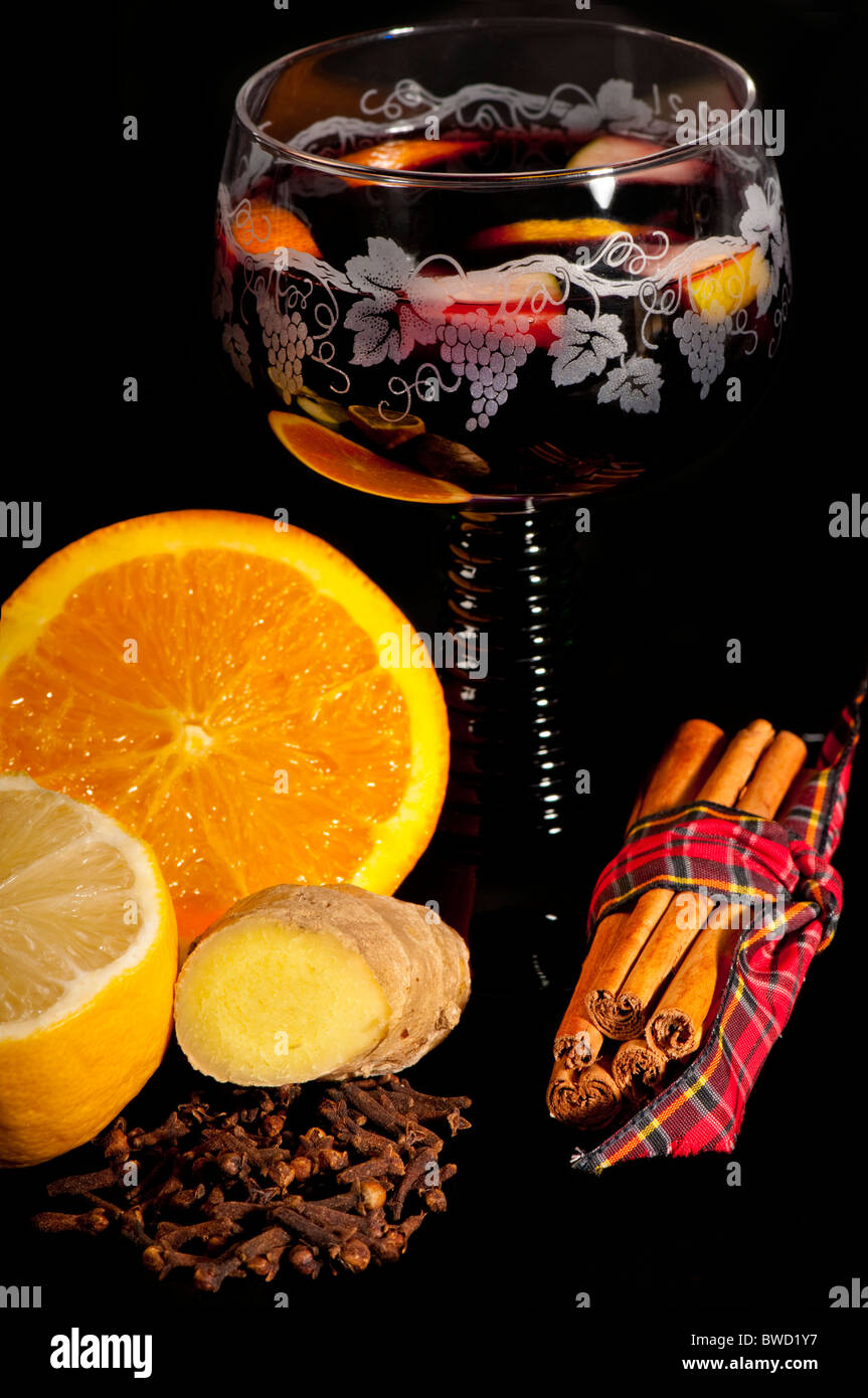Traditionnel vin chaud dans un verre vert allemand est entouré par les ingrédients : orange, citron, cannelle, girofle, gingembre. Banque D'Images