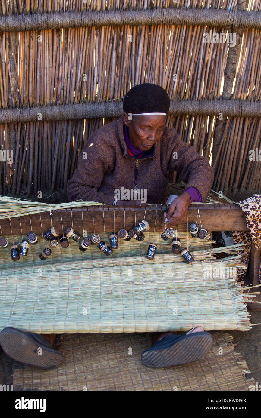 Swazi traditionnel Femme tissant un tapis avec les batteries comme poids Banque D'Images