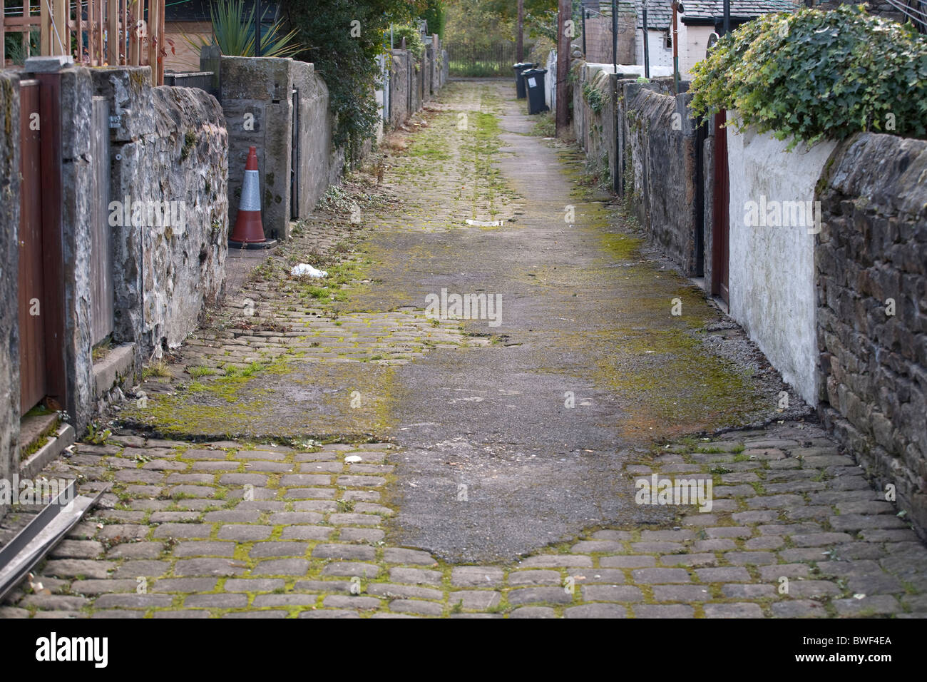 Rue pavées partiellement ginnel entre les rues de maisons mitoyennes dans une ville anglaise du nord Banque D'Images