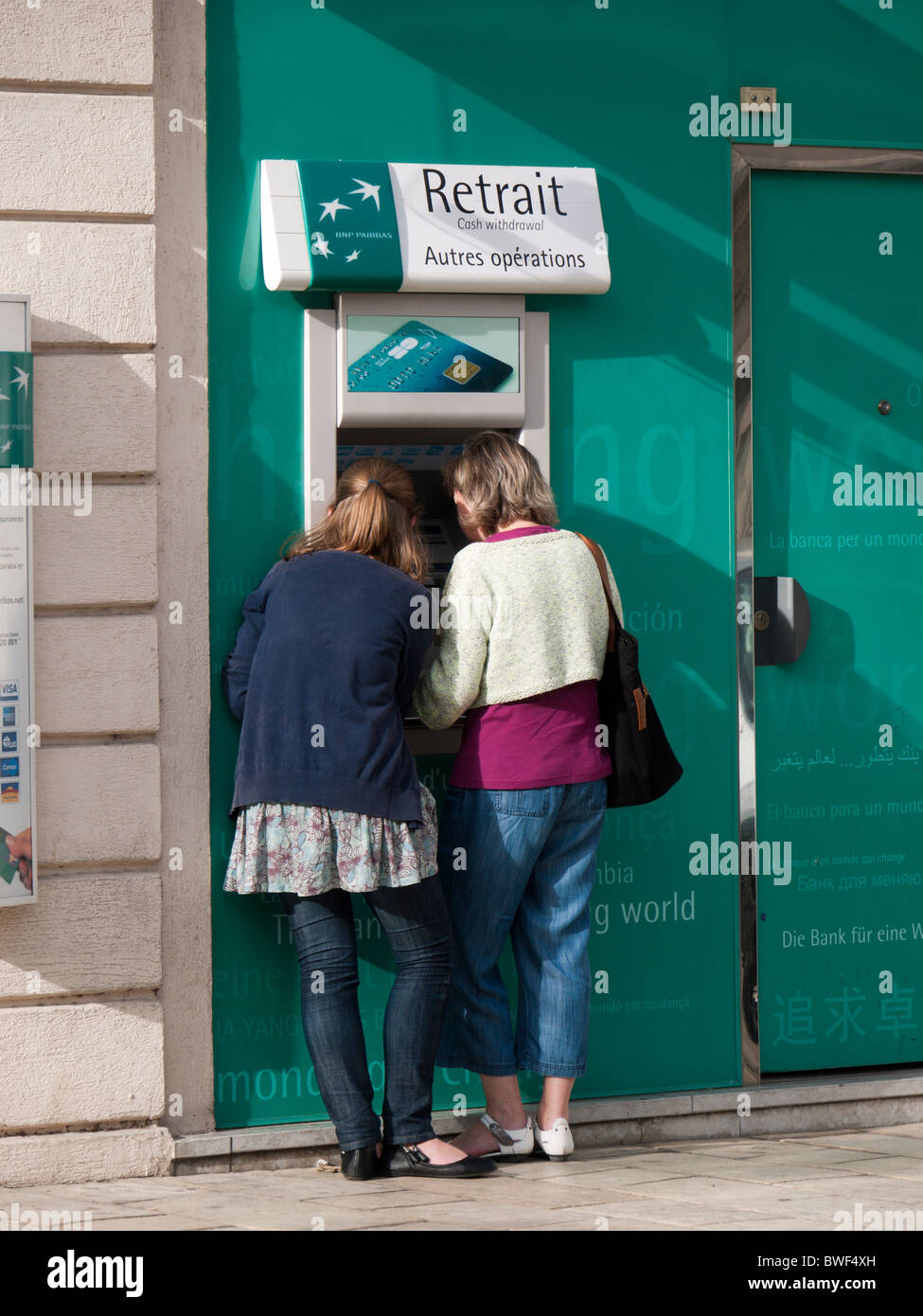 Deux femmes retirer de l'argent dans un distributeur automatique d'un BNP Paribas, France Banque D'Images