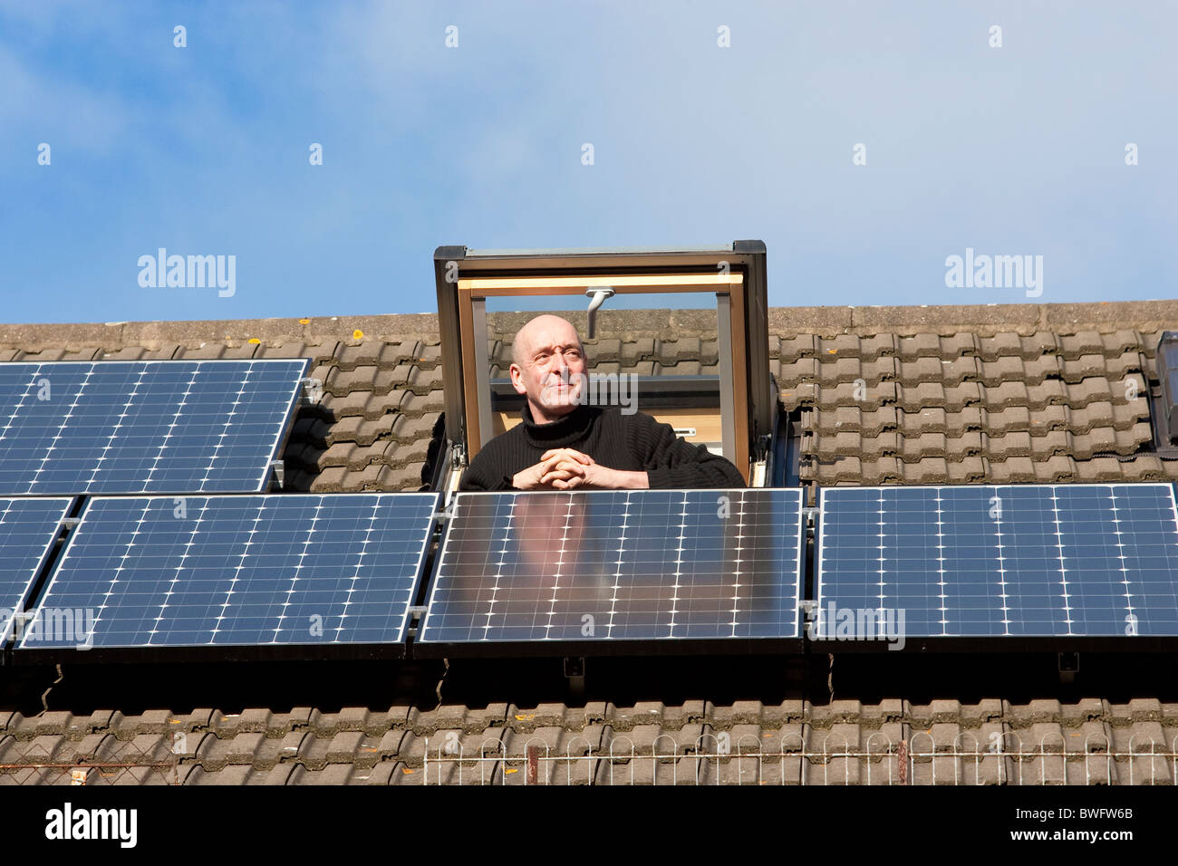 L'homme regarde par la fenêtre Velux plus Accueil l'énergie solaire panneaux solaires sur son toit à Londres, Royaume-Uni. Photo:Jeff Gilbert Banque D'Images