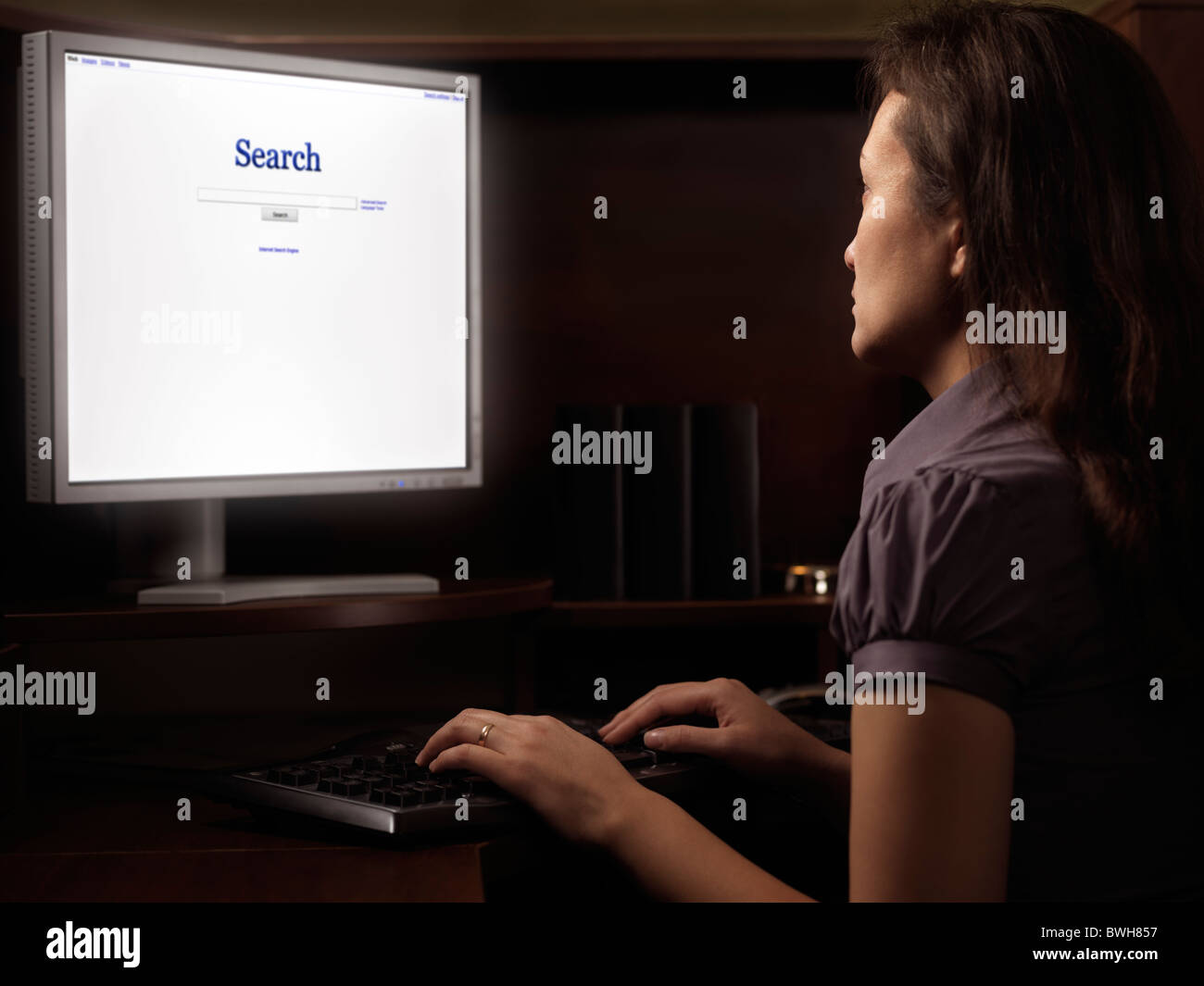Jeune femme assise à un bureau informatique avec internet Moteur de recherche sur l'affichage Banque D'Images