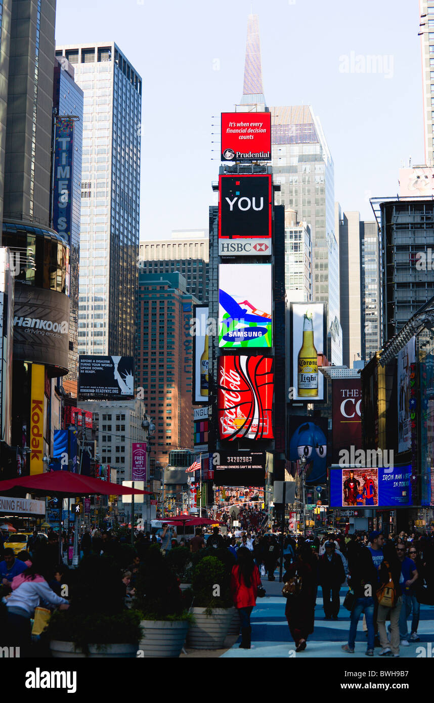 USA, New York, Manhattan, personnes marchant dans Times Square à la jonction de la 7e Avenue et Broadway en dessous des écrans publicitaires Banque D'Images