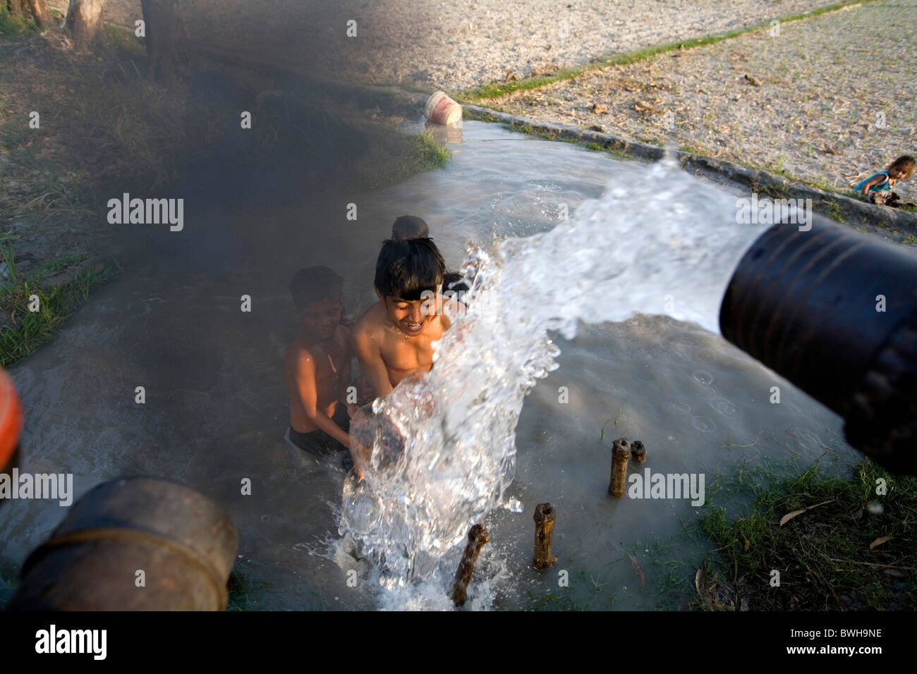 Les enfants ayant une douche sous une pompe fonctionne avec un moteur diesel au Népal Banque D'Images