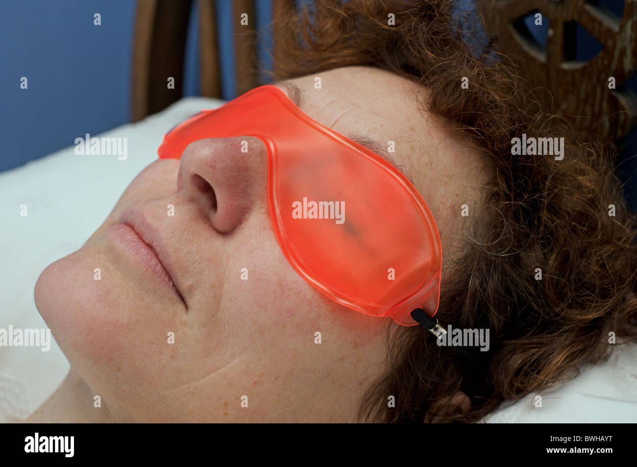 Femme portant un masque gel pour les yeux de refroidissement qui refroidit autour des yeux après une fin de nuit Banque D'Images