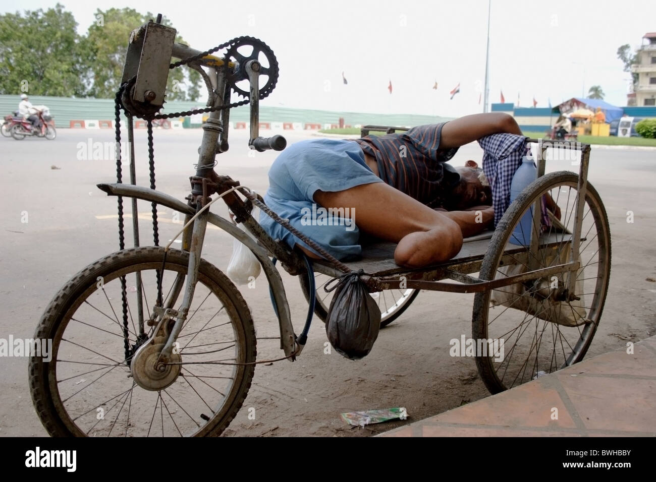 Un double amputé l'homme vivant dans la pauvreté est en train de dormir dans un fauteuil roulant par le Mékong, promenade à Phnom Penh, Cambodge. Banque D'Images