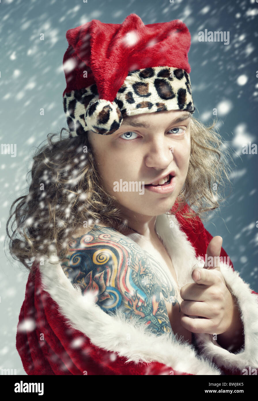 Mauvais homme avec différentes couleurs de tatouage dans le costume rouge du Père Noël, sous la tempête Banque D'Images