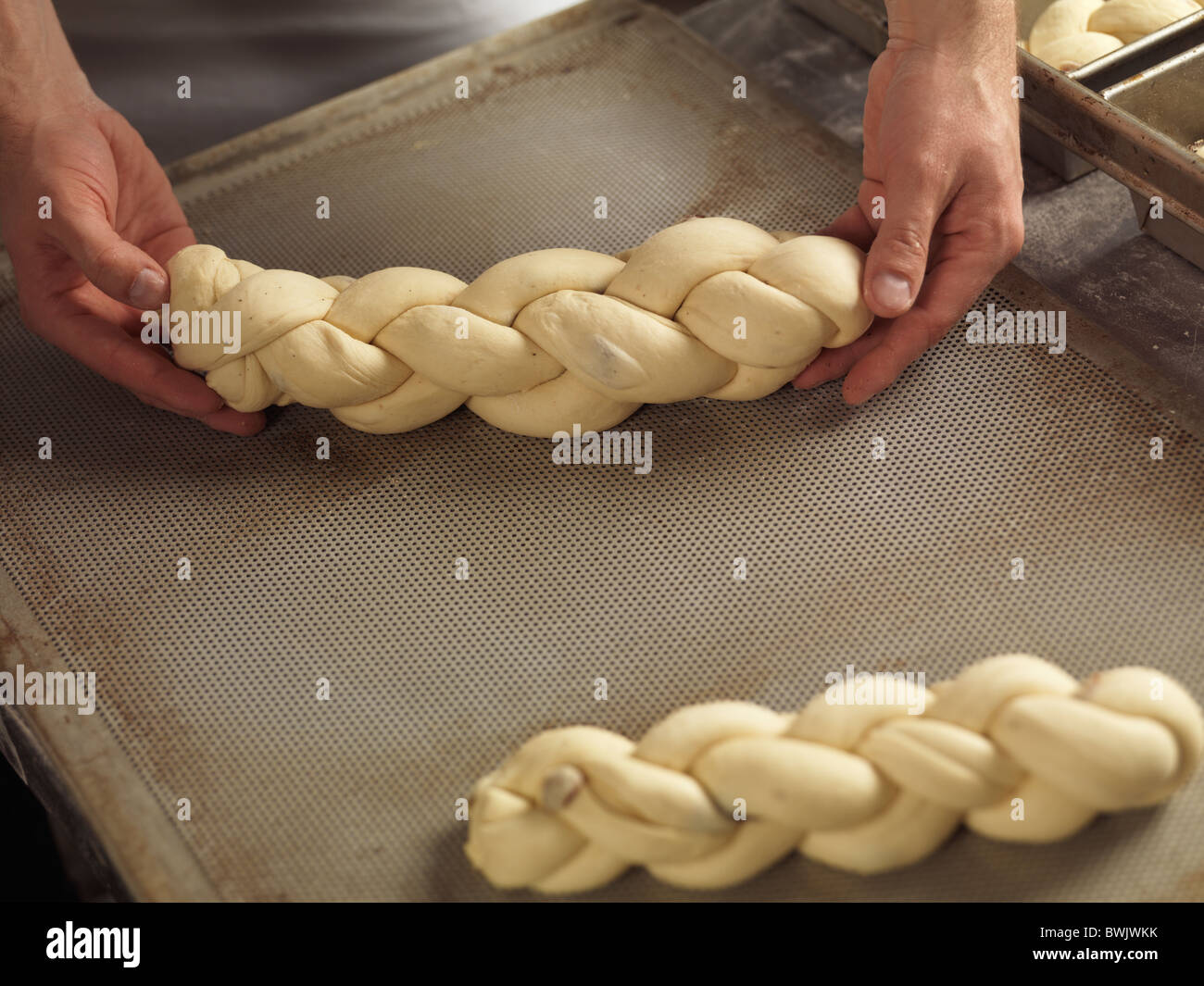 Libre de boulangers pose les mains pain tressé challah sur une plaque de cuisson Banque D'Images