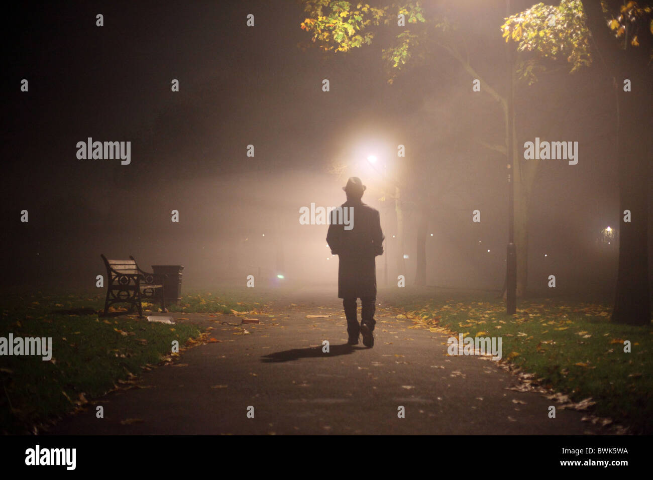 Homme trench-coat avec chapeau et dans le parc Banque D'Images