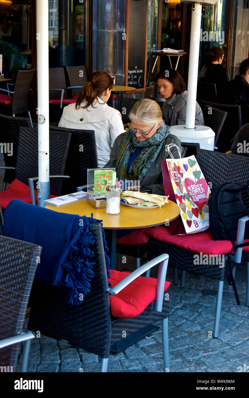 Patron femme assis au restaurant patio extérieur avec table big sandwich au jambon et au fromage de la vieille ville de Leipzig Banque D'Images