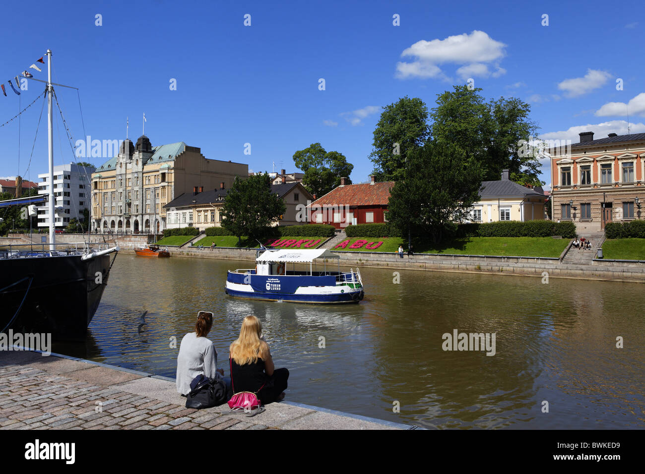 Deux jeunes femmes assises sur les rives de la rivière situé, Turku, Finlande Banque D'Images