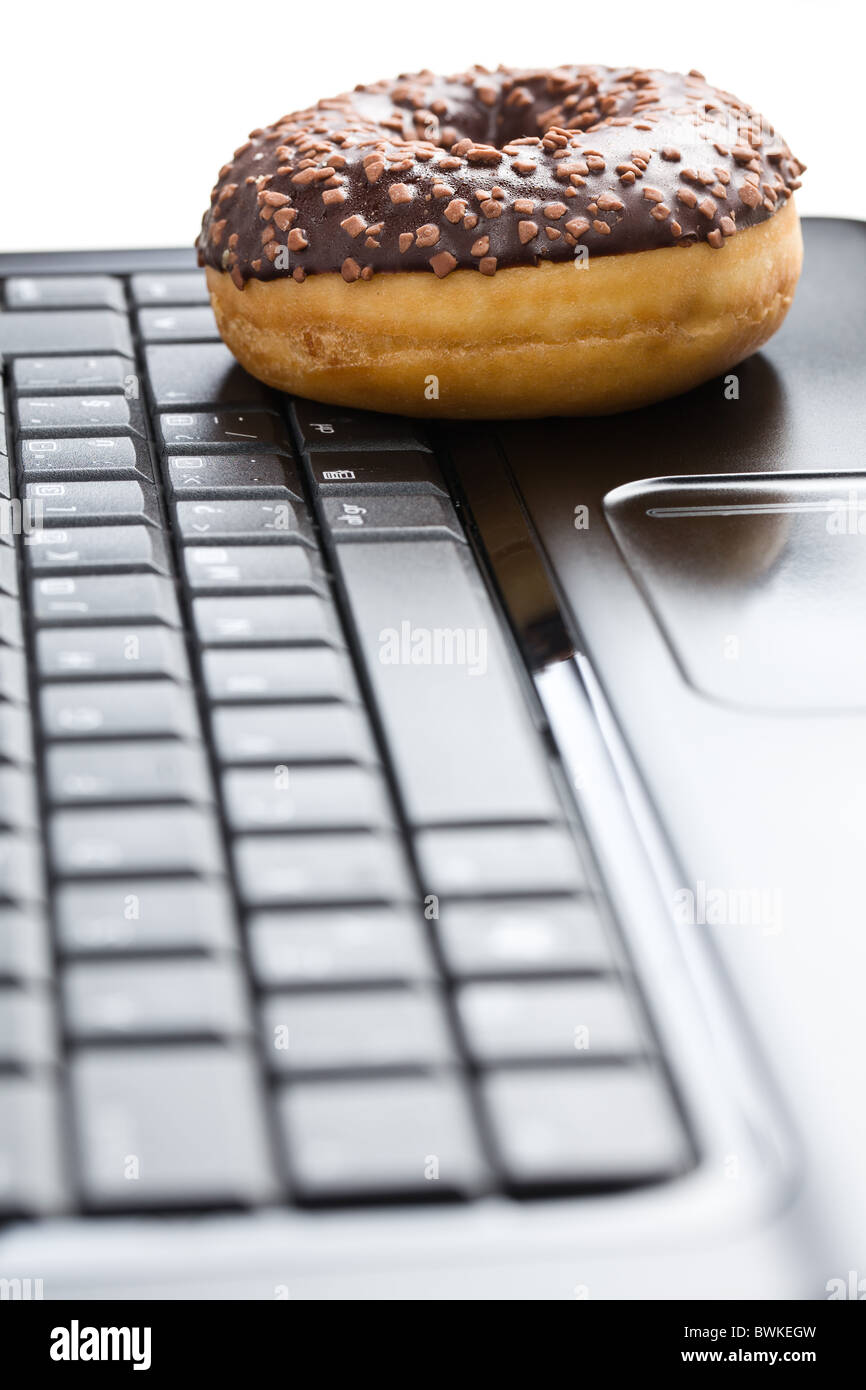 La pause au bureau . donut sur clavier d'ordinateur portable Banque D'Images