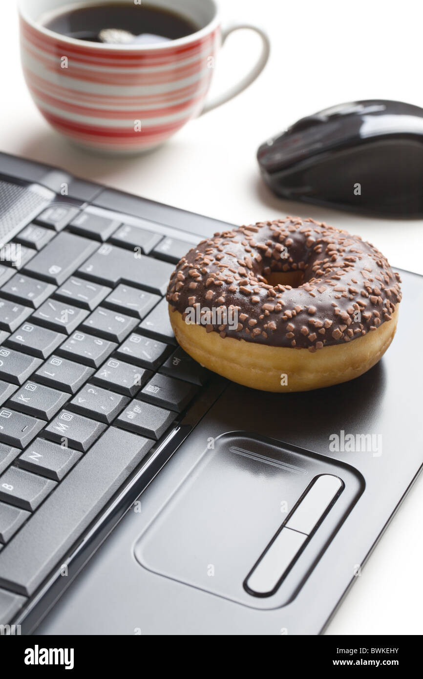 La pause au bureau . donut sur clavier d'ordinateur portable Banque D'Images