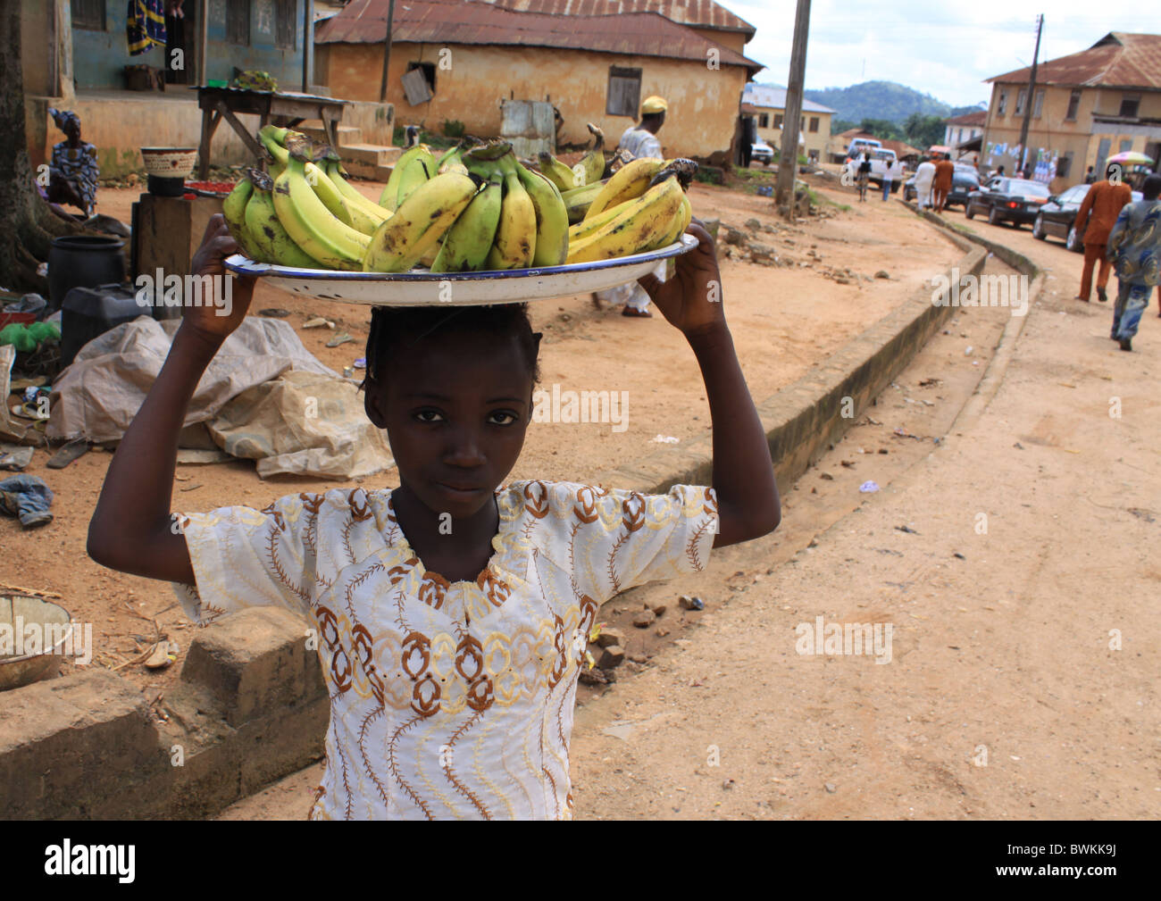 Une fillette nigériane fonctionne par hawking plantain pour aider avec l'entretien de la famille le long de la rue en Ikoro Ekiti, Nigeria. Banque D'Images