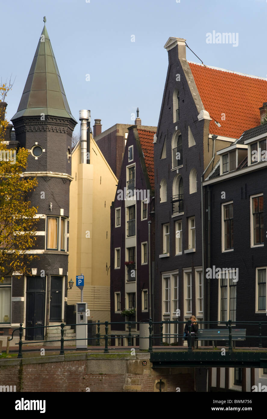 Scène au bord du canal à Amsterdam, Hollande, avec tour pointue et bâtiments de tuiles rouges. Banque D'Images