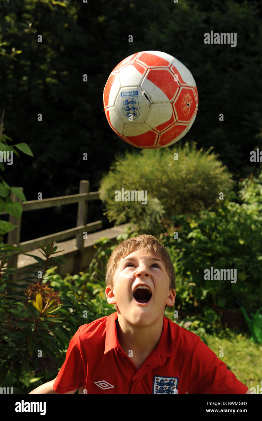 Un garçon de dix ans joue au football dans le jardin modèle entièrement libéré/consenti Banque D'Images