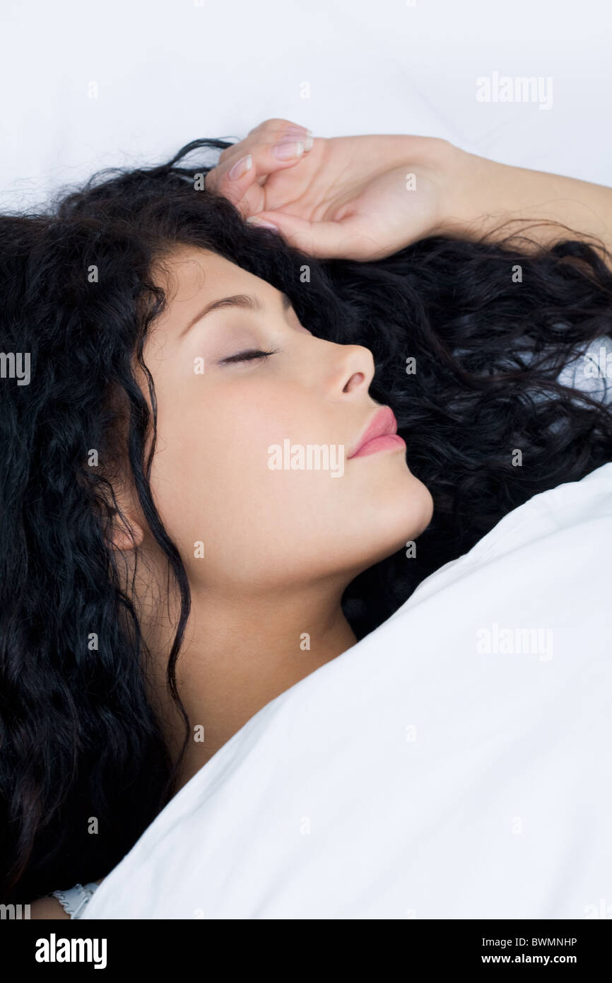 Photo de femme sereine dormir paisiblement dans les draps blancs Banque D'Images