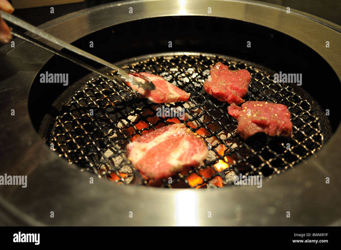 Un restaurant barbecue coréen boeuf cuisson patron sur le gril de table. Tokyo, Japon. Banque D'Images