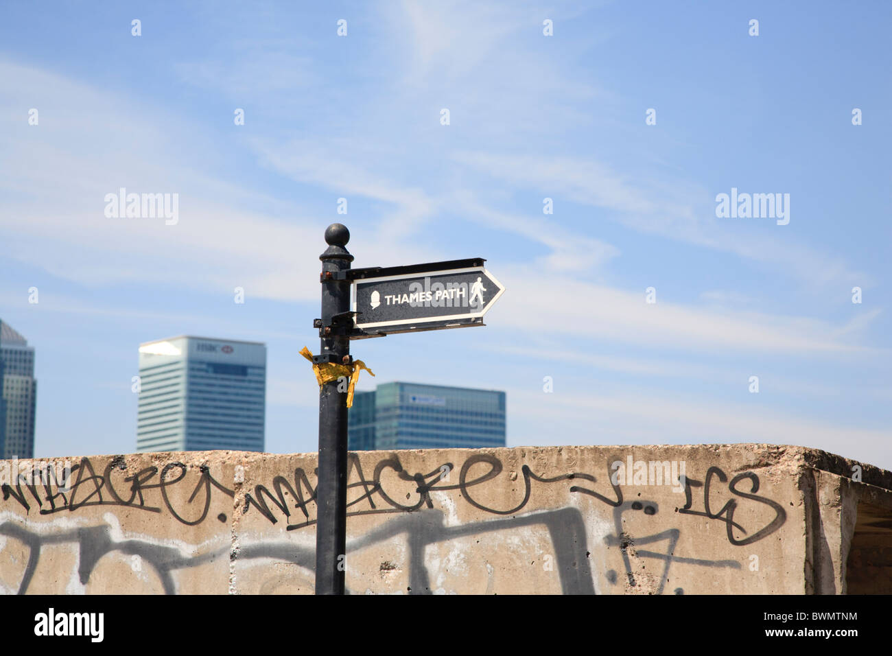 Thames path signe avec les tours de Canary Wharf et de graffitis dans l'arrière-plan Banque D'Images