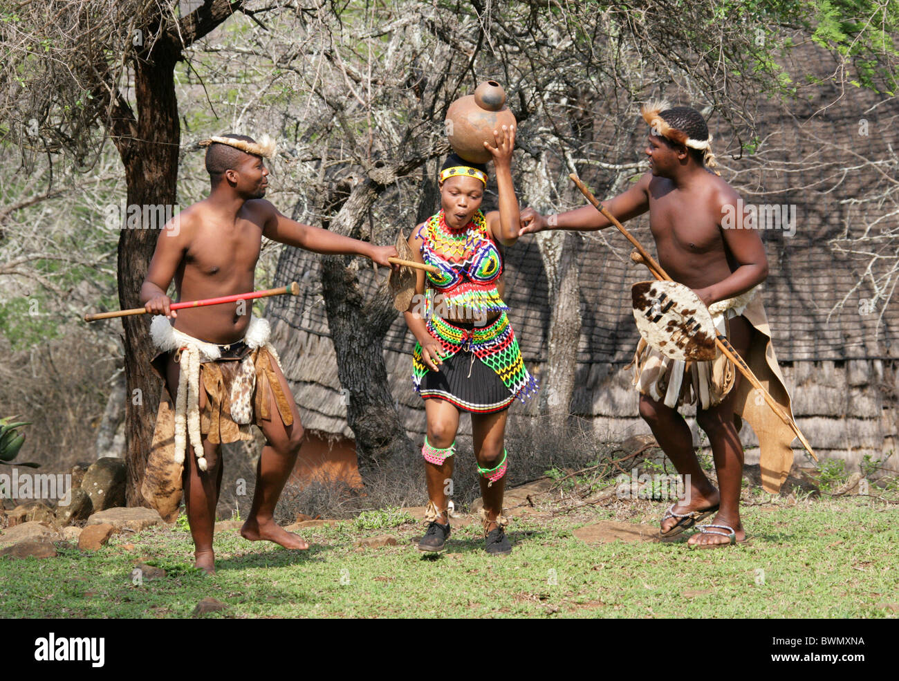 Les jeunes guerriers zoulous flirter avec une jeune fille, Zoulou zoulou de Shakaland, Village Vallée Nkwalini, Kwazulu Natal, Afrique du Sud. Banque D'Images