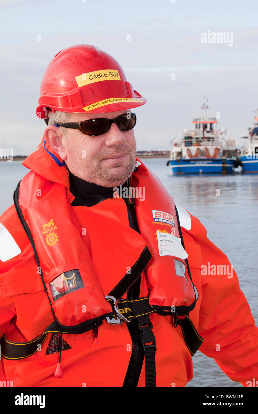 Un travailleur étranger sur son chemin hors de l'éolien offshore Walney le port de vêtements protecteurs, Barrow in Furness, Cumbria, Royaume-Uni. Banque D'Images