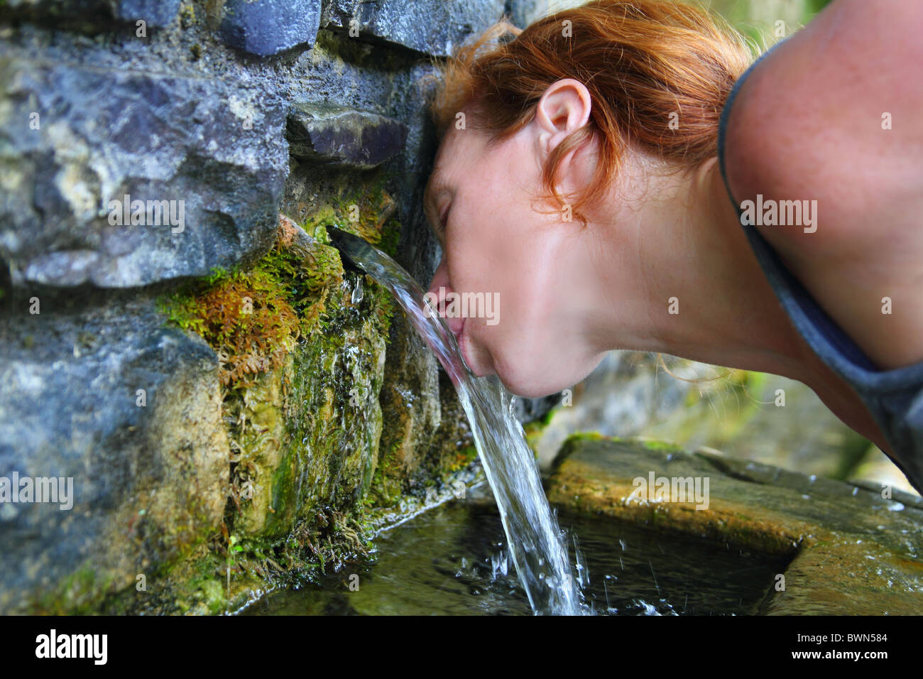 Source de l'eau de source potable femme en montagne de Pyrénées Banque D'Images