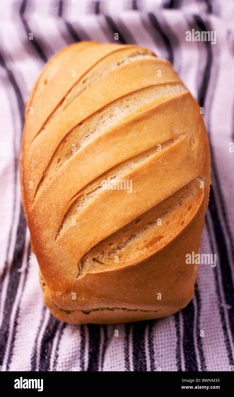 Un pain fraîchement cuit croustillant de pain au levain repose sur un torchon à rayures. Banque D'Images