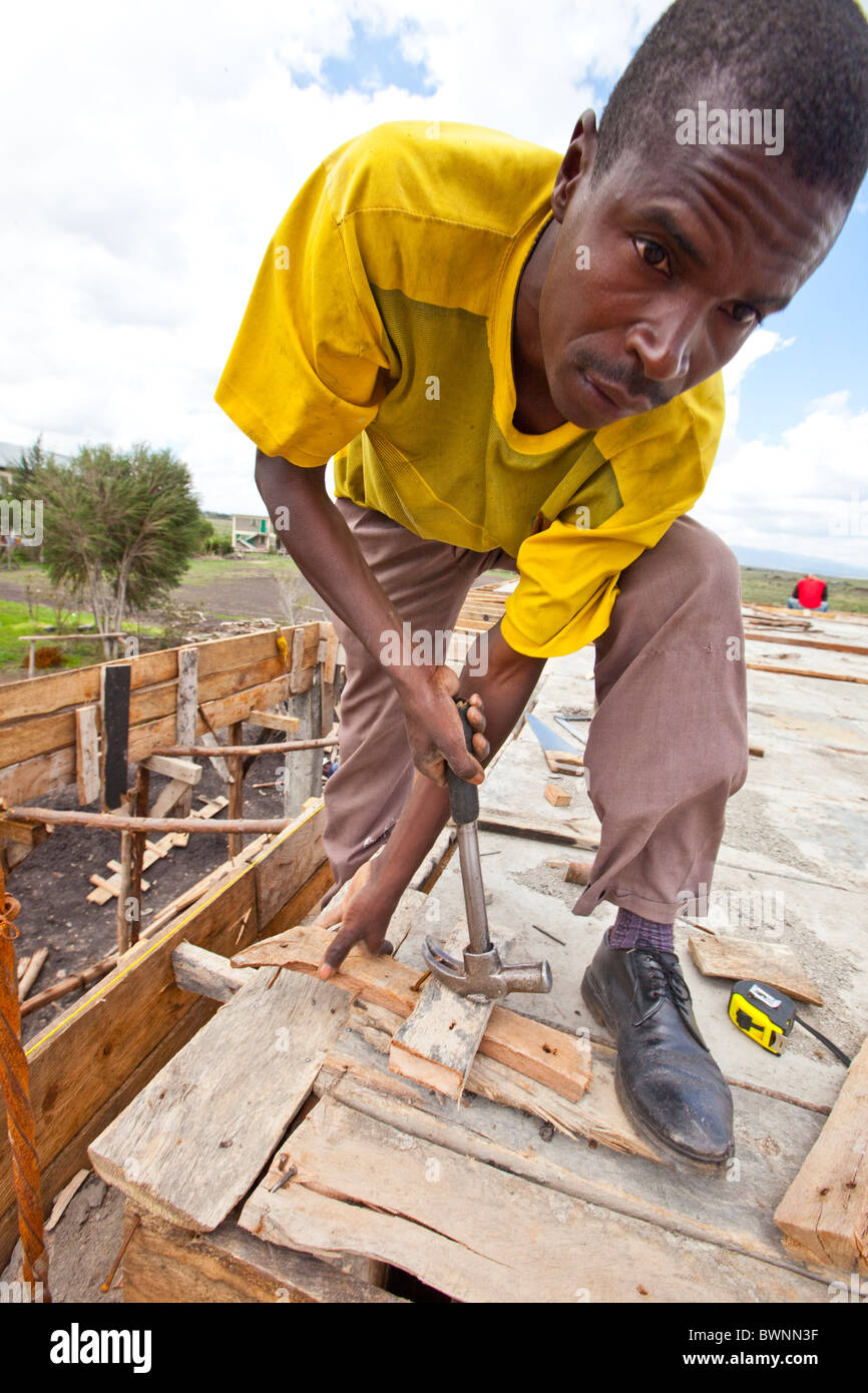 Workman aidant à construire un bâtiment à Maji Mazuir centre et école, Nairobi, Kenya Banque D'Images