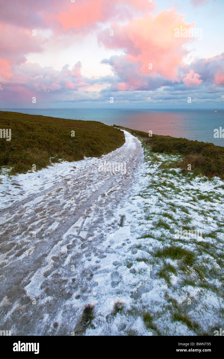 La neige sur le sentier des falaises de Howth, comté de Dublin, Irlande. Mer et beaux nuages colorés en arrière-plan. Banque D'Images