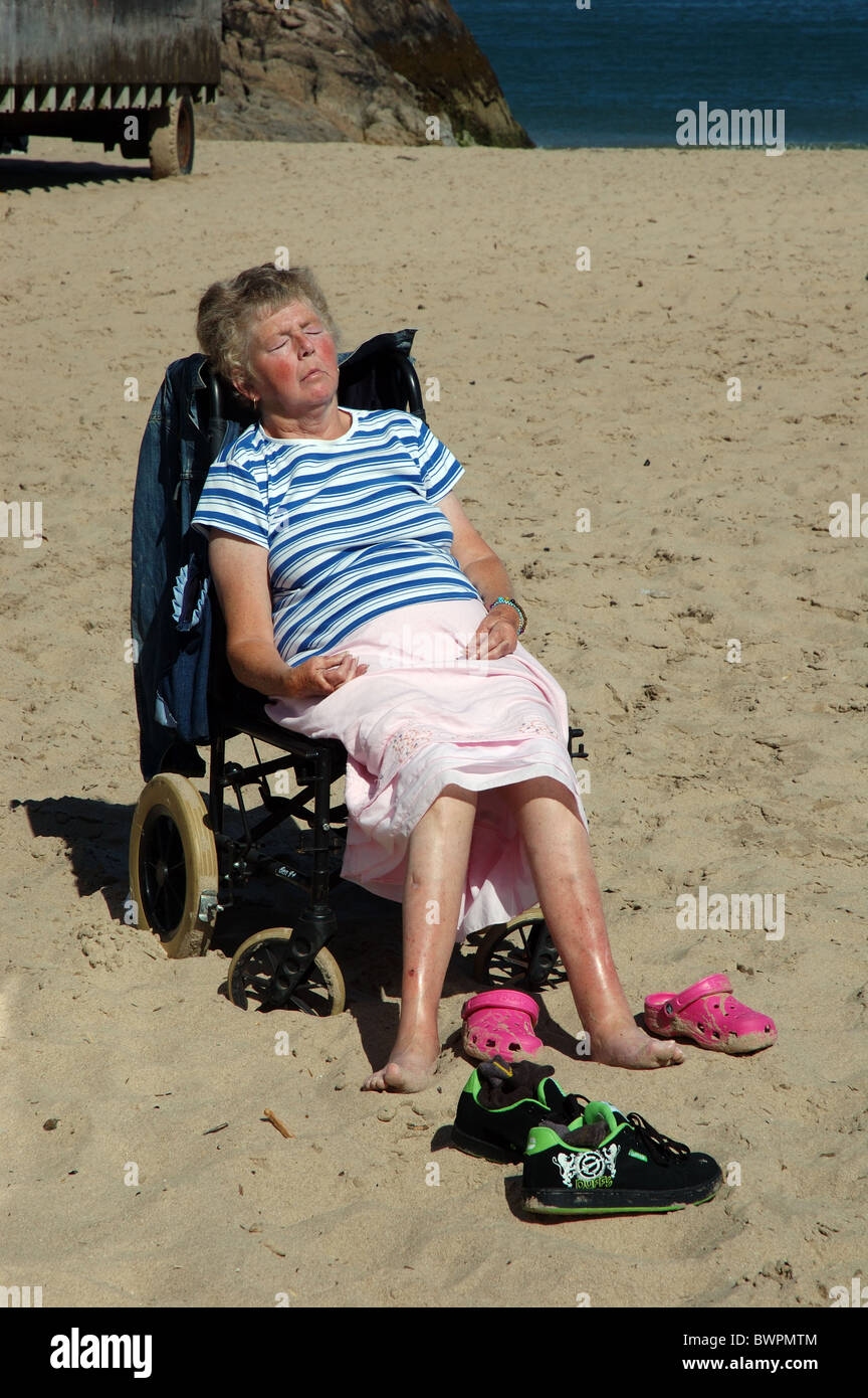 Senior lady sunbathing on beach, Tenby, Pembrokeshire, Pays de Galles, Royaume-Uni Banque D'Images