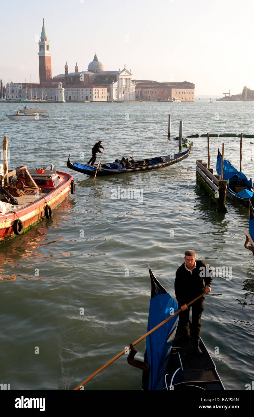 Gondoliers au travail dans le bassin de Saint-Marc avec San Giorgio Maggiore en arrière-plan. Banque D'Images