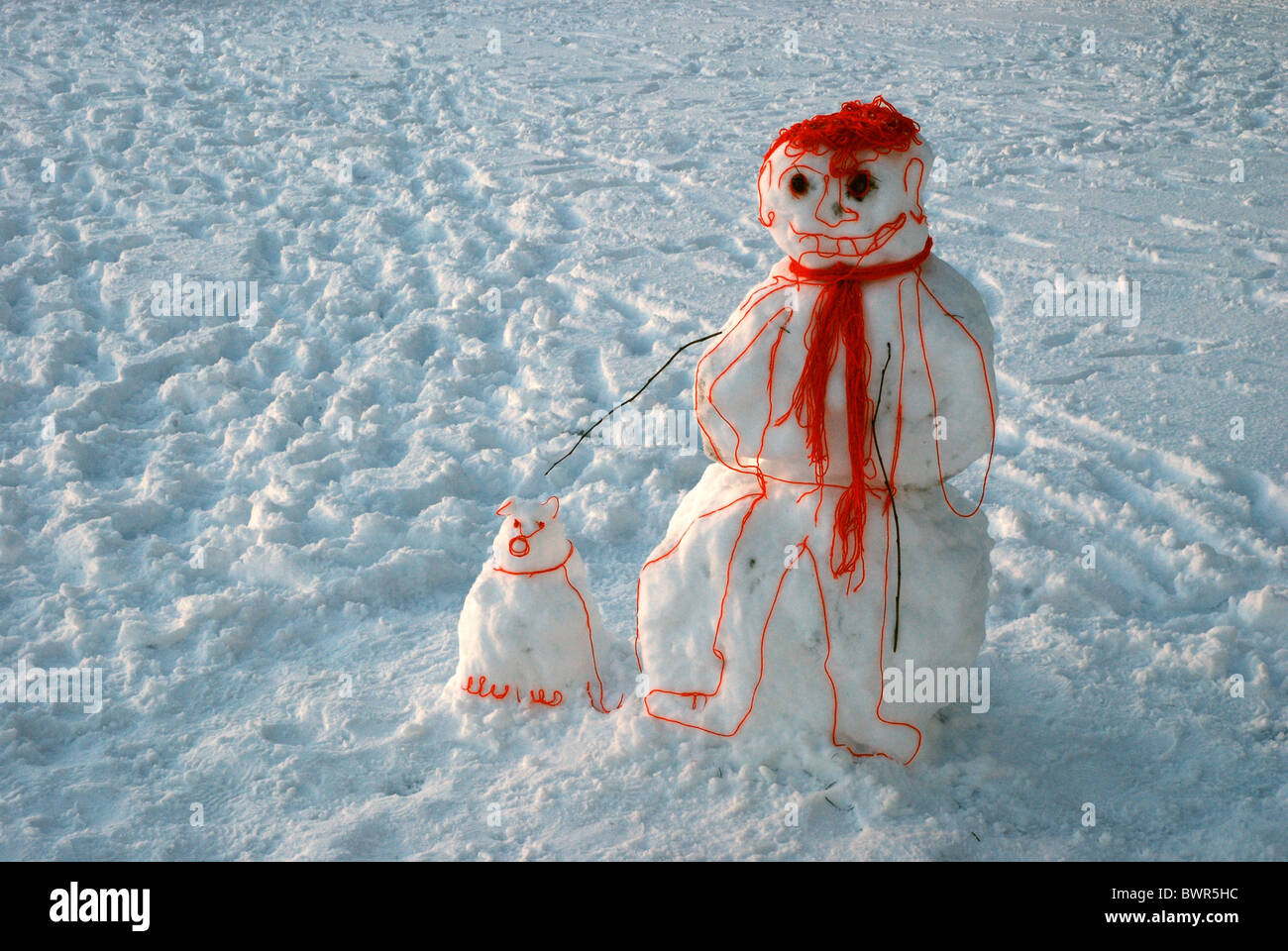 Un 'cartoon' bonhomme avec son chien, fait de la neige et de la laine, debout dans les prés à Édimbourg, Écosse, Royaume-Uni. Banque D'Images